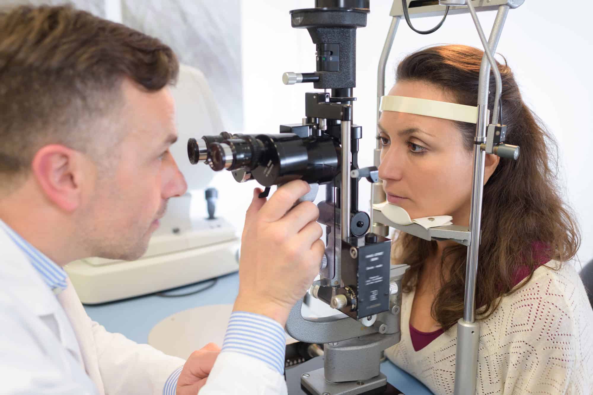 Augenarzt untersucht Frau mit einem augenärztlichen Gerät