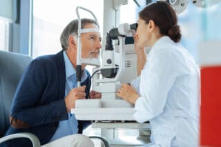 braunhaarige Augenärztin untersucht die Augen eines Mannes